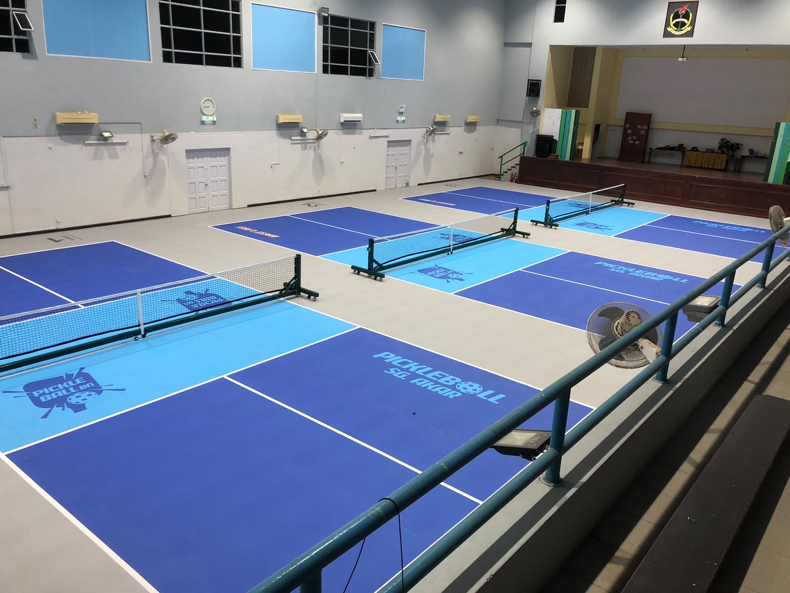 Three indoor pickleball courts at PGGMB Hall Sg. Akar with nets and PickleballBN court branding