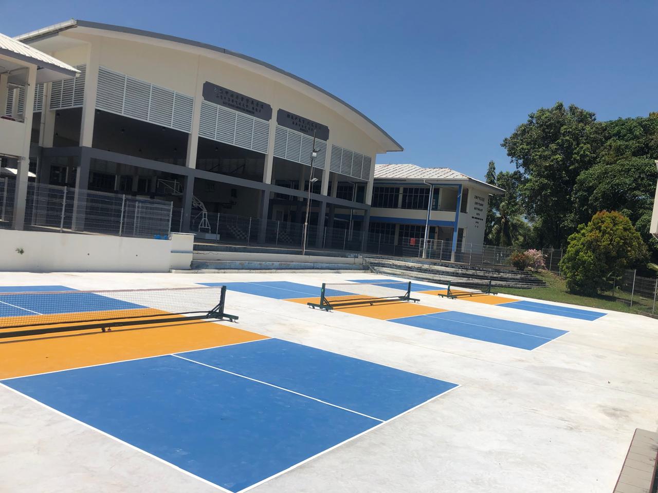 Court-level view of orange and blue pickleball surface at Tutong